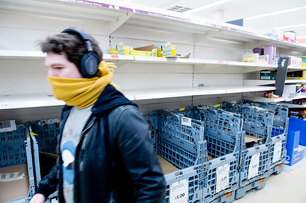 Британский покупатель с импровизированной маской на лице возле пустых полок с молочными продуктами в лондонском магазине Sainsburys. Продажи жизненно важных товаров и медицинских средств распределяются по лондонским магазинам определенными партиями, чтобы избегать дефицита