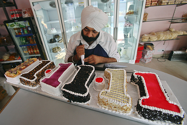 Кондитер из индийского города Панчкула наносит последние штрихи, украшая торт, испеченный специально к дате 11.11.11