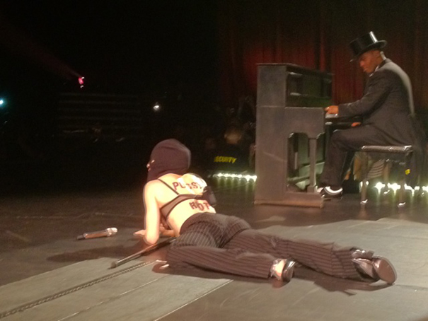 Певица также натянула на голову черную ткань, легла на сцену и продолжала петь в таком положении