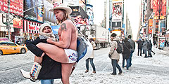 Уличный актер Роберт Берк, также известный как Голый Ковбой, позирует с женщиной после снегопада. Несмотря на мороз, он, как обычно, в одних трусах появился на Таймс-Сквер в Нью-Йорке. Голый Ковбой (Naked Cowboy) уже много лет является живой достопримечательностью Таймс-Сквер. С 1998-го в любую погоду  365 дней в году он играет на гитаре, поет и фотографируется с туристами в своем фирменном наряде: ковбойских сапогах, стенсонской шляпе и белых трусах.  Уличный артист утверждает, что только на чаевых зарабатывает до 150 000 долларов в год