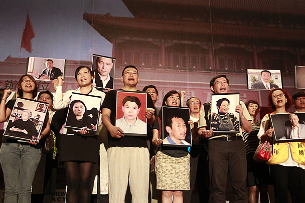 Люди с портретами политзаключенных Китая, принявшие участие в ночном бдении на площади Свободы в Тайбэе