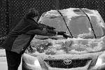 Женщина соскребает образовавшийся лед с лобового стекла своего автомобиля, припаркованного возле продуктового магазина в Миннеаполисе&#160;(фото: Reuters)
