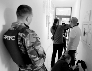 Охранник и журналисты у офиса РИА «Новости Украина» в Киеве, где СБУ проводит обыски
